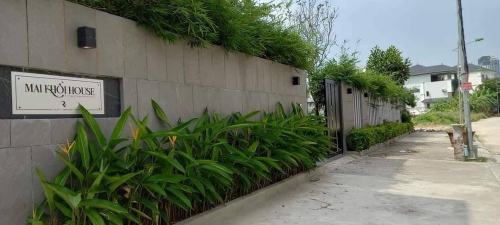 

Căn biệt thự được gắn bảng tên ở bức tường trước cửa, xung quanh là hàng cây xanh
