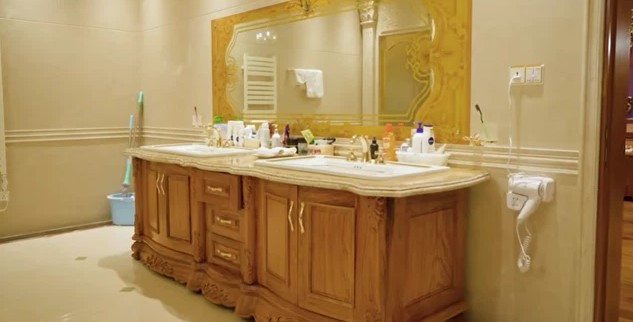 
Nằm trong căn nhà có chứa đầy loại gỗ quý hiếm nên ở khu vực bồn rửa trong nhà tắm cũng được lắp đặt một chiếc tủ gỗ quý, phần trên mặt được dát vàng
