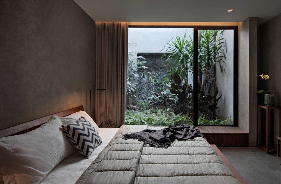 
Một không gian phòng ngủ có cửa sổ hướng ra phần non bộ trong nhà
