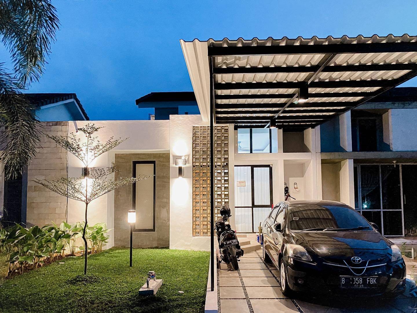 
Căn nhà hai tầng với thiết kế hiện đại với các đường nét vuông vắn, có thảm cỏ xanh và gara để xe phía trước
