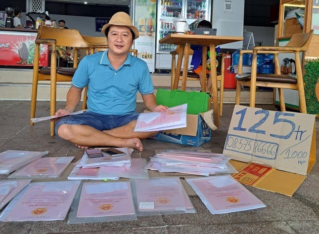 
Anh Nguyễn Hữu Trí bày sổ đỏ của các khách hàng ký gửi ra vỉa hè để bán (ảnh Báo Tiền phong)
